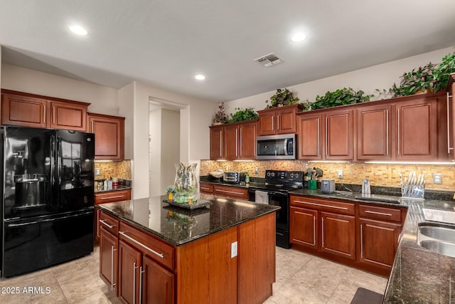 kitchen featuring visible vents, decorative backsplash, a kitchen island, dark stone counters, and black appliances