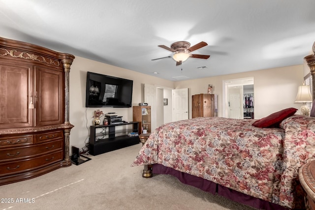 bedroom featuring ceiling fan, a spacious closet, visible vents, and light colored carpet