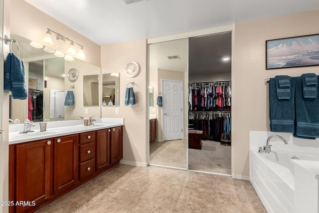 bathroom with a bath, double vanity, a sink, and visible vents