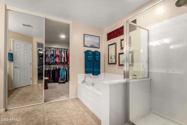 full bathroom with a stall shower, a garden tub, visible vents, and a walk in closet