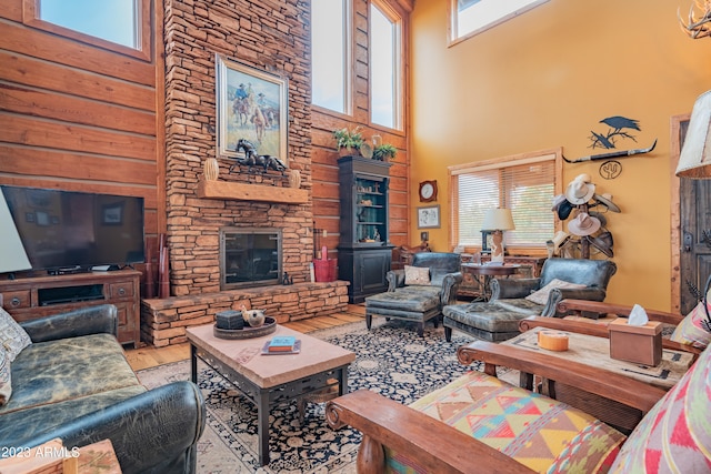 living room featuring a stone fireplace, light wood-type flooring, and a towering ceiling