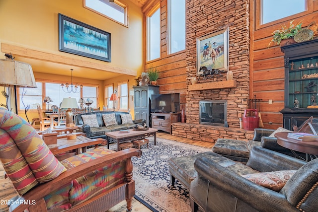 living room featuring a towering ceiling, wood walls, an inviting chandelier, a stone fireplace, and hardwood / wood-style flooring