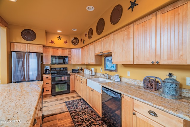 kitchen featuring light hardwood / wood-style flooring, light stone countertops, light brown cabinets, and black appliances