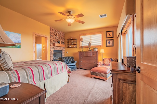 bedroom with carpet, ceiling fan, and a stone fireplace