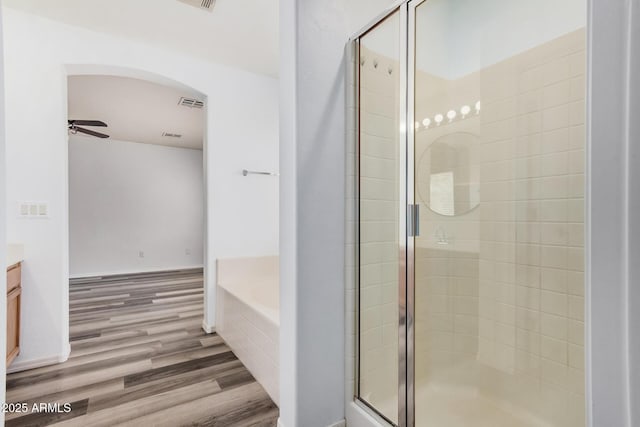 bathroom with a garden tub, visible vents, wood finished floors, a shower stall, and a ceiling fan
