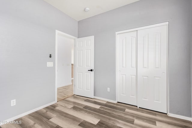unfurnished bedroom with a closet, baseboards, and wood finished floors