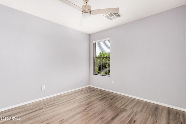 spare room featuring baseboards, wood finished floors, and visible vents