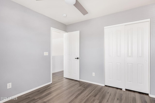 unfurnished bedroom featuring a closet, a ceiling fan, baseboards, and wood finished floors