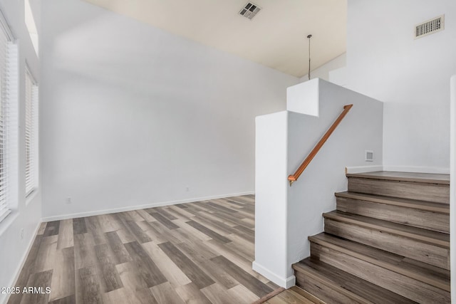 stairway featuring baseboards, wood finished floors, and visible vents