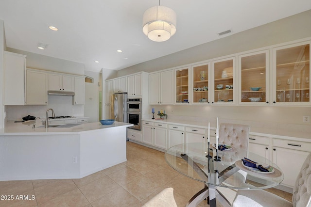 kitchen featuring decorative light fixtures, white cabinetry, light countertops, appliances with stainless steel finishes, and glass insert cabinets