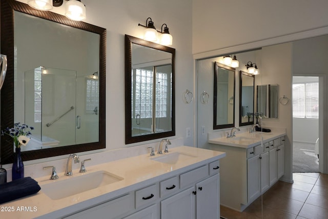 bathroom with tile patterned flooring, a sink, a shower stall, and double vanity