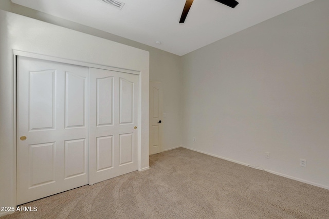 unfurnished bedroom featuring ceiling fan, light carpet, visible vents, baseboards, and a closet