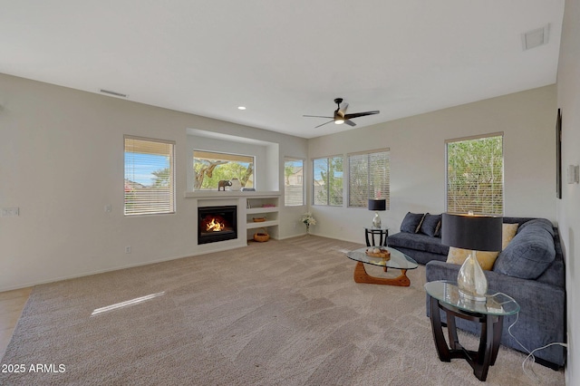 living area with light colored carpet, visible vents, a lit fireplace, and recessed lighting