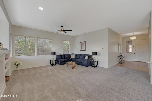 living room with ceiling fan, light tile patterned floors, a wealth of natural light, and light colored carpet