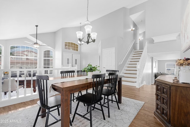 dining space featuring light wood-style floors, plenty of natural light, stairs, and ceiling fan with notable chandelier