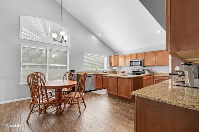 kitchen with appliances with stainless steel finishes, a center island, brown cabinets, and wood finished floors