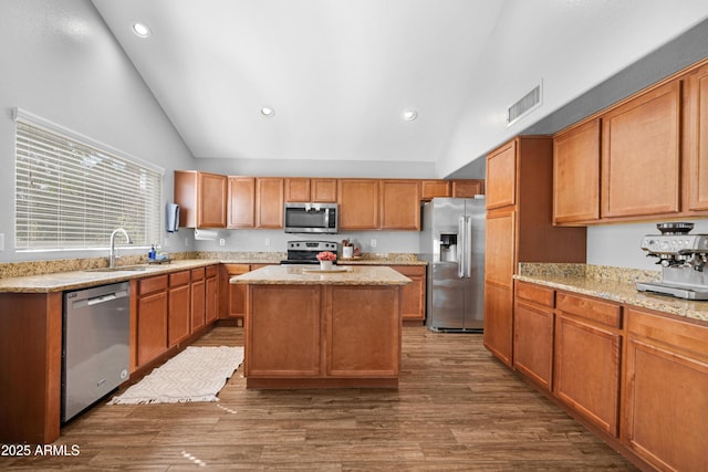 kitchen with a kitchen island, a sink, visible vents, appliances with stainless steel finishes, and dark wood finished floors