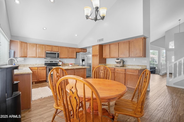 kitchen with a notable chandelier, a kitchen island, visible vents, appliances with stainless steel finishes, and light wood finished floors