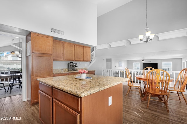 kitchen with a center island, dark wood-style flooring, visible vents, high vaulted ceiling, and ceiling fan with notable chandelier