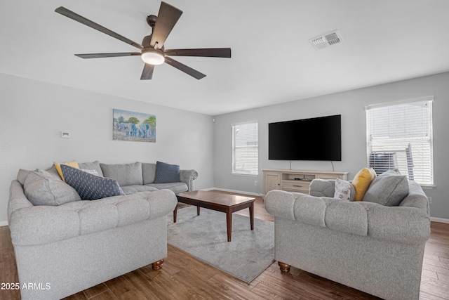 living area featuring baseboards, dark wood finished floors, visible vents, and a ceiling fan