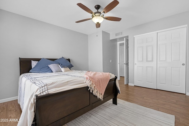 bedroom with ceiling fan, wood finished floors, visible vents, and baseboards