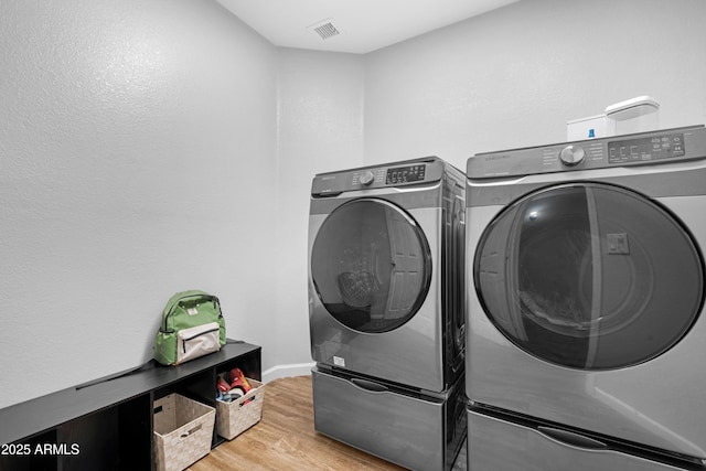 washroom with laundry area, visible vents, independent washer and dryer, and wood finished floors