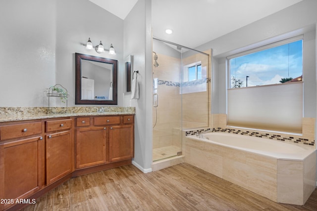 full bath featuring a shower stall, vanity, a bath, and wood finished floors