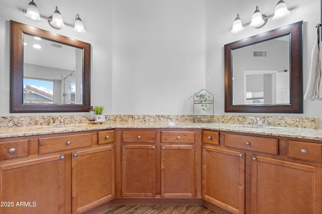 bathroom featuring double vanity, wood finished floors, a sink, and visible vents