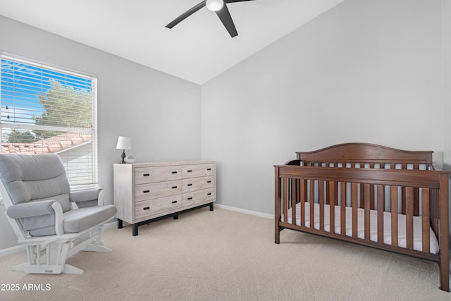 carpeted bedroom with a ceiling fan, lofted ceiling, a crib, and baseboards