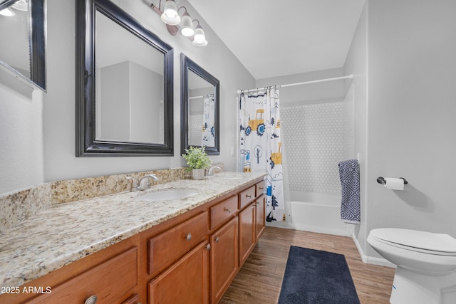 bathroom with double vanity, wood finished floors, a sink, and toilet