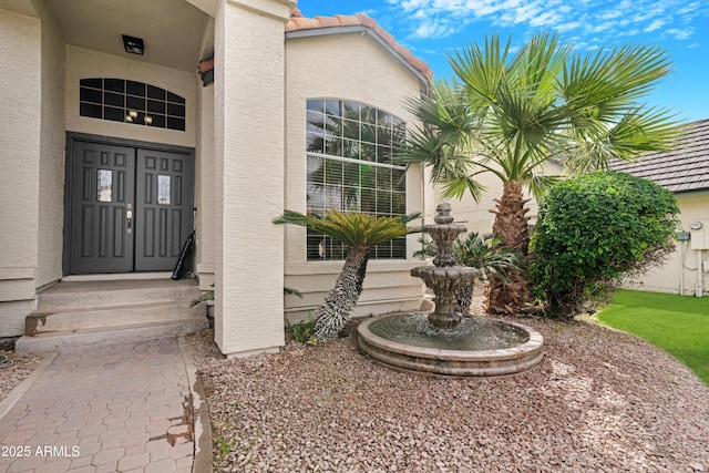 doorway to property featuring a tiled roof and stucco siding