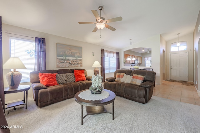 tiled living room featuring ceiling fan with notable chandelier and lofted ceiling