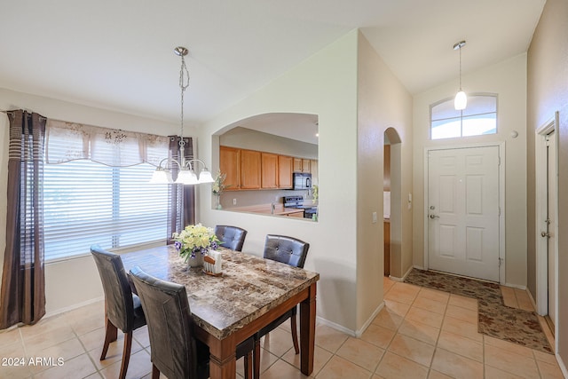 dining space featuring light tile patterned flooring, a chandelier, and vaulted ceiling