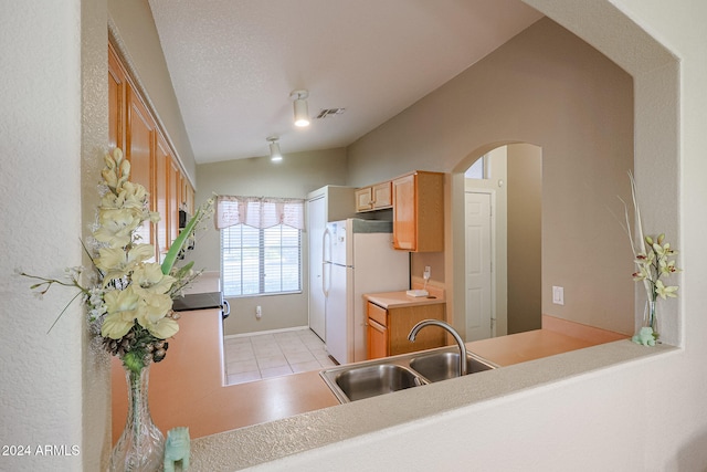 kitchen with vaulted ceiling, a textured ceiling, sink, light tile patterned flooring, and white fridge