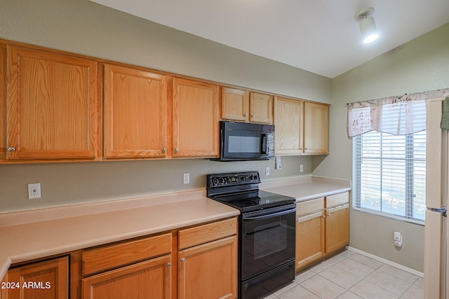 kitchen featuring light tile patterned floors, black appliances, and vaulted ceiling