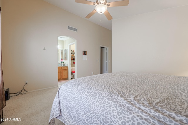 bedroom featuring a towering ceiling, ensuite bath, light carpet, and ceiling fan