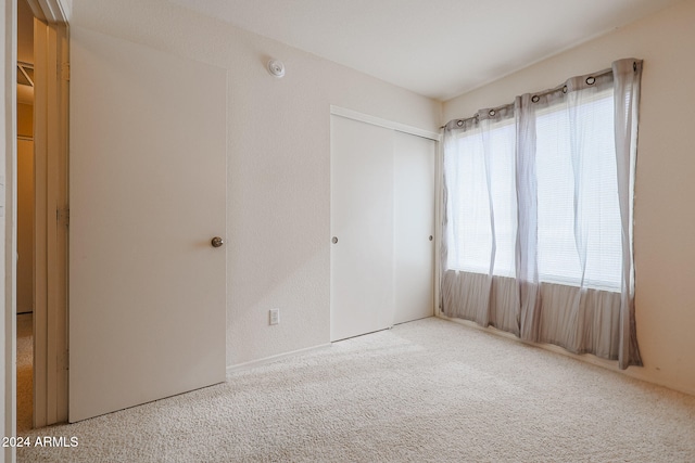 unfurnished bedroom featuring multiple windows, a closet, and carpet flooring