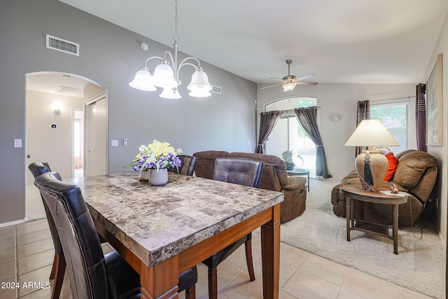 dining room with ceiling fan with notable chandelier, light carpet, and lofted ceiling