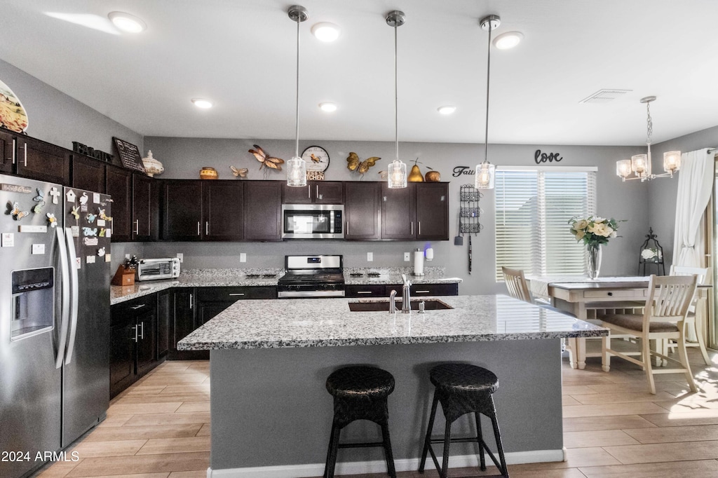 kitchen featuring sink, stainless steel appliances, a center island with sink, and light hardwood / wood-style flooring