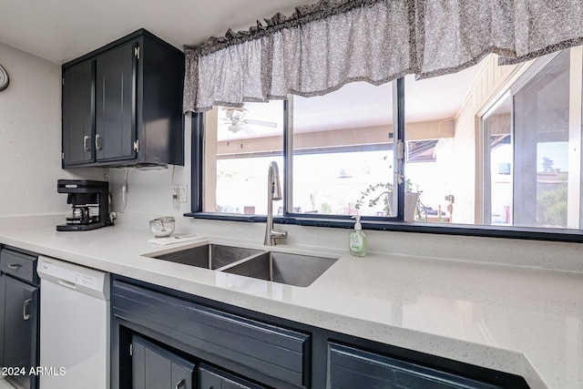 kitchen with light stone counters, white dishwasher, and sink