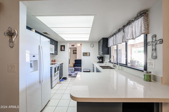 kitchen featuring kitchen peninsula, light tile patterned floors, sink, and white appliances