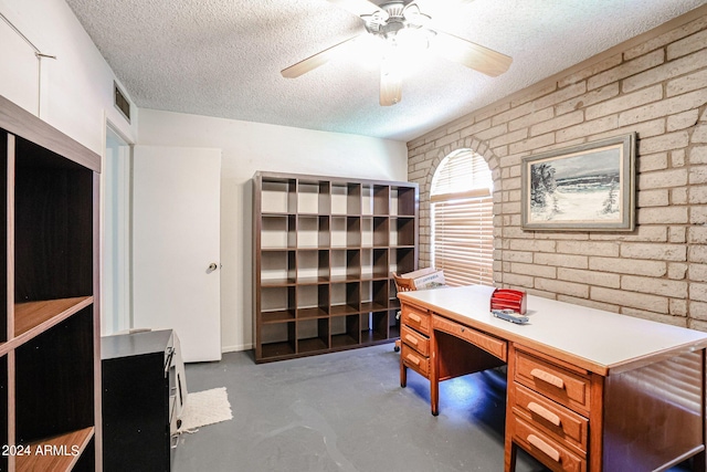 office space with a textured ceiling, ceiling fan, and brick wall