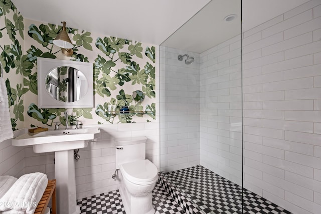 bathroom featuring tile walls, toilet, and tiled shower