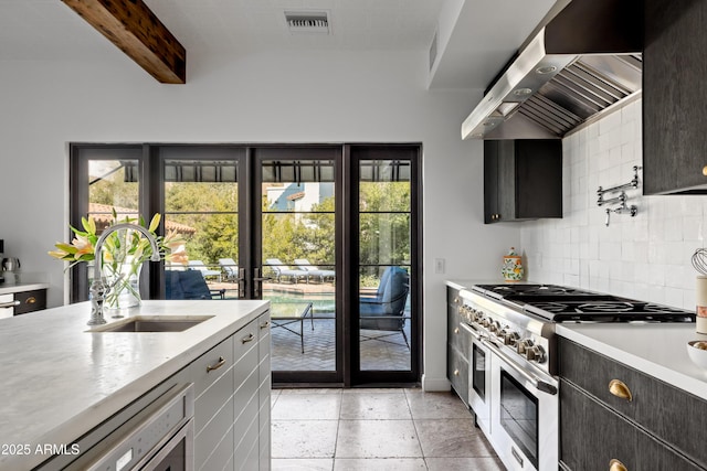 kitchen featuring high end stainless steel range, sink, tasteful backsplash, beamed ceiling, and wall chimney range hood