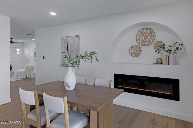 dining area with recessed lighting, a ceiling fan, wood finished floors, and a glass covered fireplace