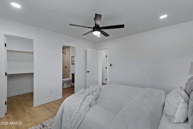 bedroom featuring recessed lighting, baseboards, a closet, light wood finished floors, and a walk in closet