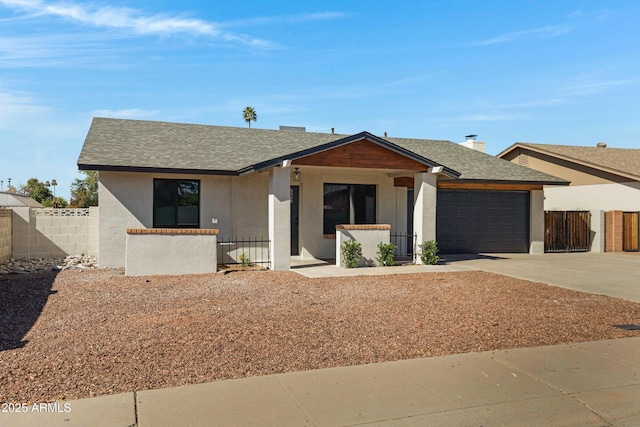 view of front of house featuring driveway, a garage, roof with shingles, fence, and stucco siding