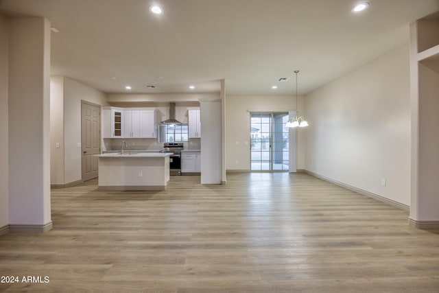 kitchen featuring stainless steel electric range oven, open floor plan, an inviting chandelier, recessed lighting, and wall chimney exhaust hood