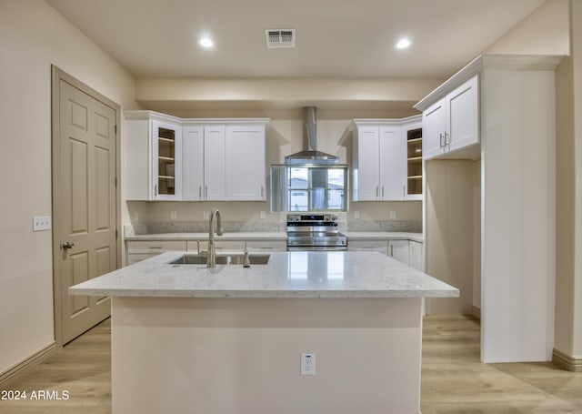 kitchen with visible vents, stainless steel electric range oven, wall chimney exhaust hood, a sink, and white cabinetry