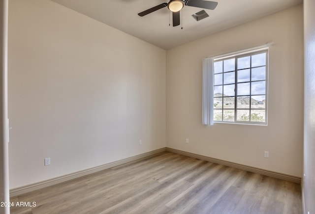 spare room with light wood-type flooring, baseboards, and ceiling fan